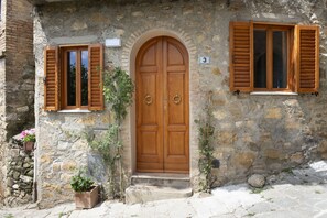 Ein Steinhaus mit einer Holztür und zwei Fensterläden.