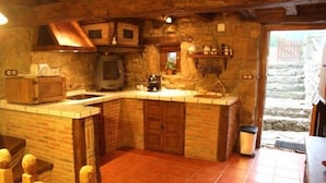 A rustic kitchen with a stone wall, wooden cabinets, and a built-in stove. - Cabin in the mountain (full rental) for 2/3 people. Pets allowed (Luena)