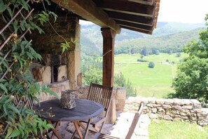 A rustic outdoor seating area with a stone wall and a view of a green valley.