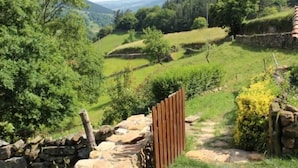 A stone wall with a wooden gate leading into a lush green valley. - Cabin in the mountain (full rental) for 2/3 people. Pets allowed (Luena)