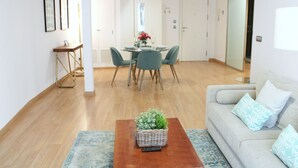 A modern living room with a dining area, a sofa, and a coffee table with a plant. - Albareda 1 - One Bedroom Apartment, Sleeps 4 (Sevilla)