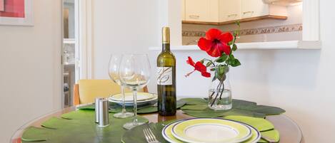 Una mesa de comedor con platos, una botella de vino, copas y un jarrón con flores.