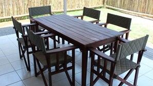 An outdoor patio with a wooden table and chairs. - Tlou Safari Lodge (Kasane)