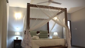 A four-poster canopy bed with a wooden frame, a bedside table with a lamp, and a bench at the foot of the bed. - Tlou Safari Lodge (Kasane)