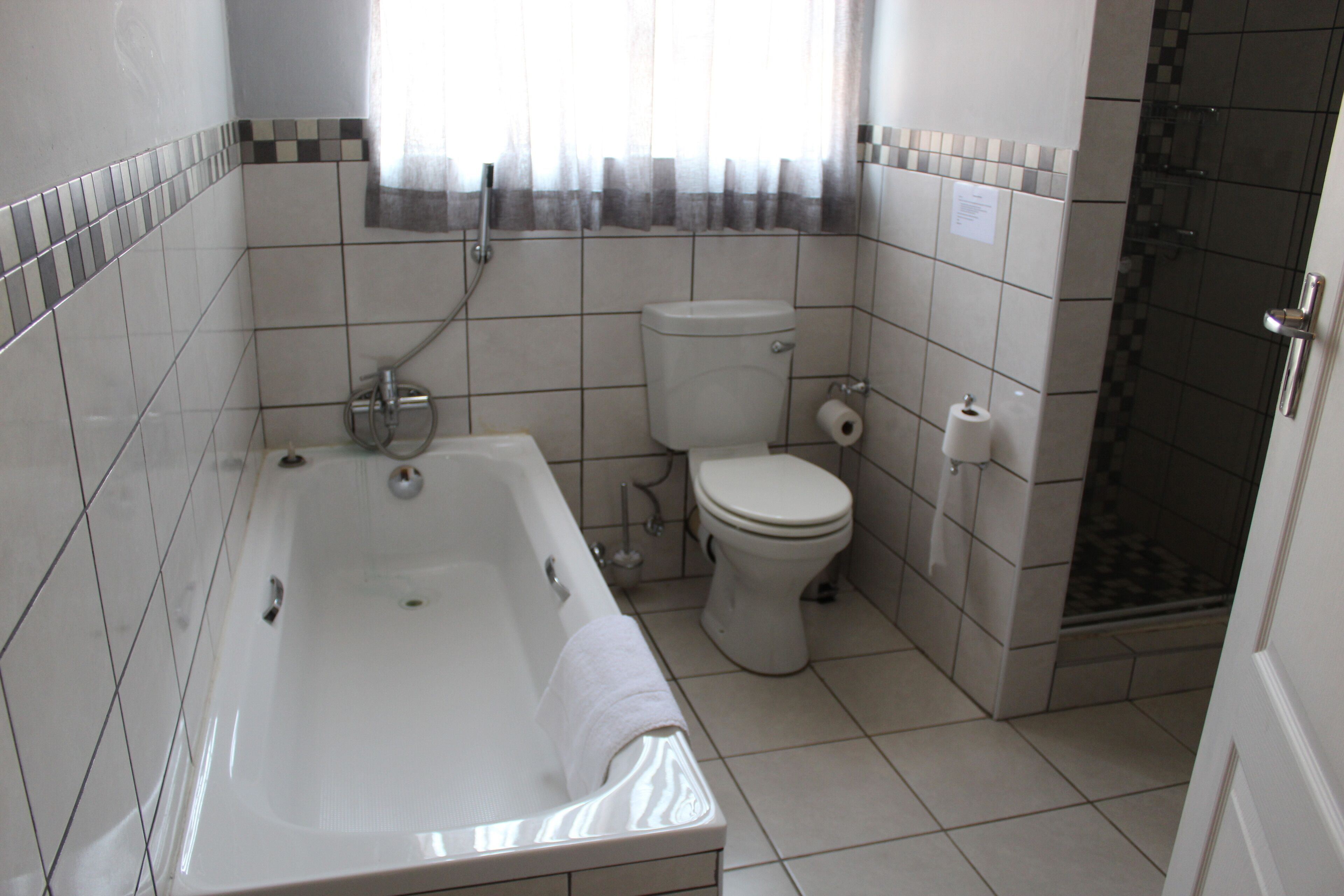Een badkamer met een bad, toilet en douche.
