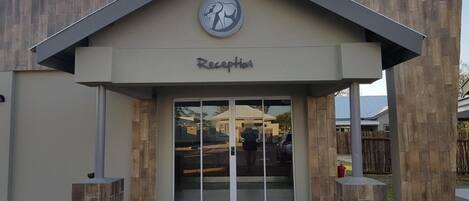 A reception area with a modern design, featuring a logo above the entrance and a clear sign indicating the reception.
