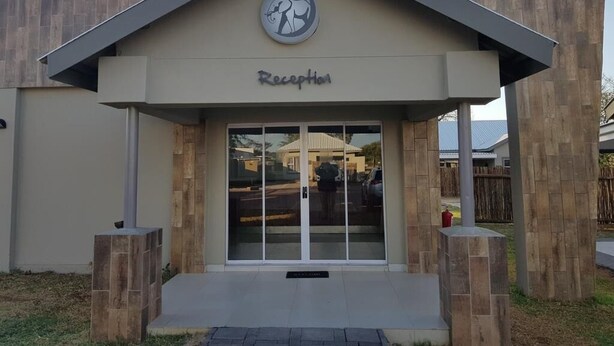 A reception area with a modern design, featuring a logo above the entrance and a clear sign indicating the reception.