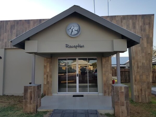 A reception area with a modern design, featuring a logo above the entrance and a clear sign indicating the reception. - Tlou Safari Lodge (Kasane)