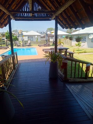 A wooden deck with a pool, potted plants, and outdoor furniture. - Tlou Safari Lodge (Kasane)