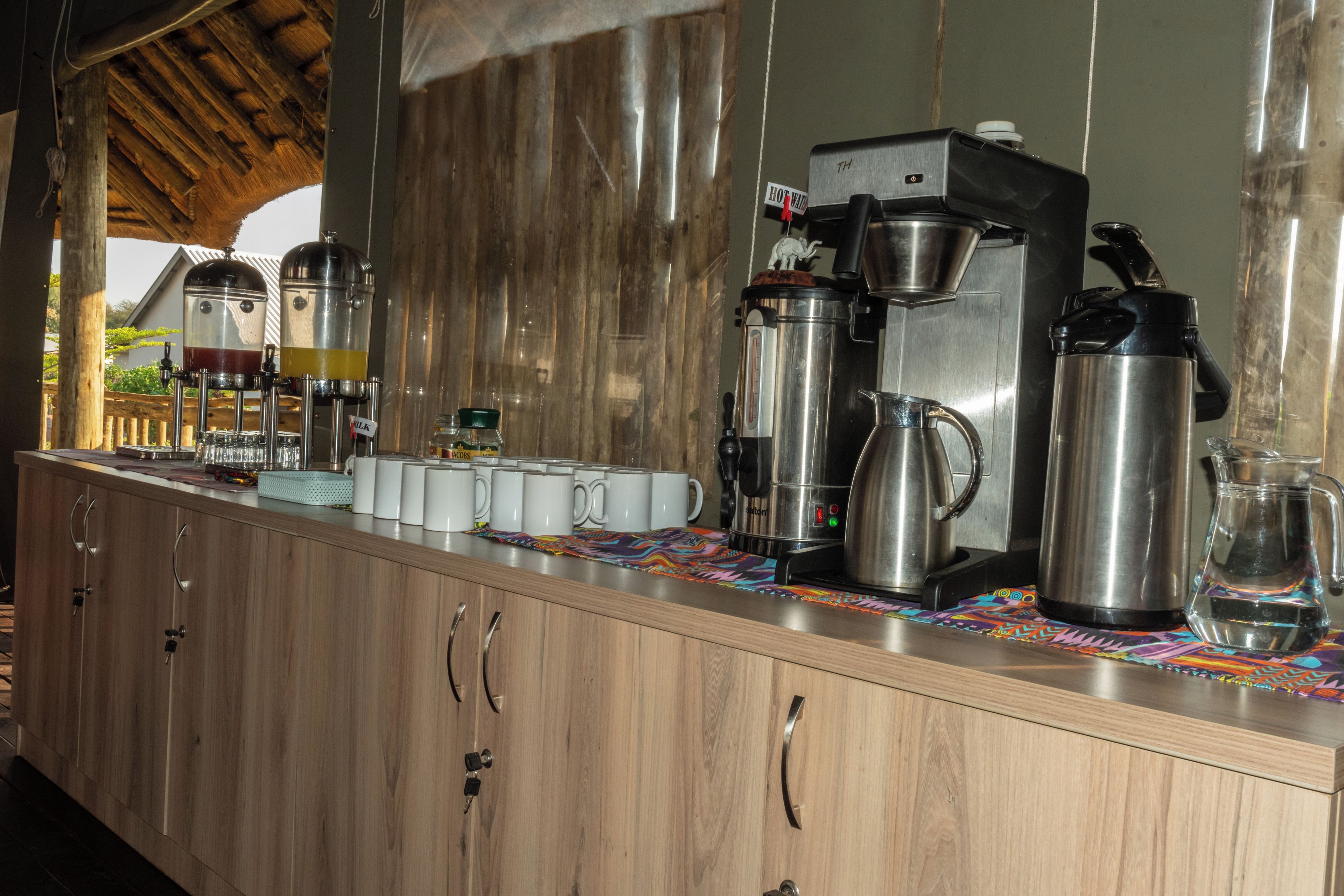 A kitchen counter with coffee-making equipment, including a coffee maker, a grinder, and a kettle.