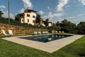 A swimming pool with lounge chairs and a hillside villa.
