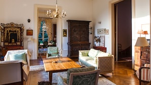 Un salón tradicional con una mesa de centro de madera, sillas tapizadas en verde y un mueble grande de madera.