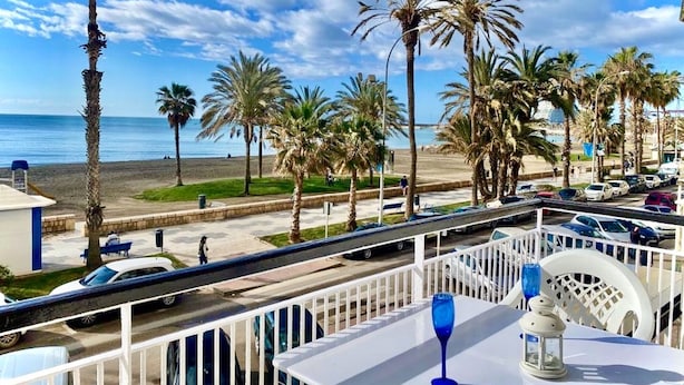 A balcony with a table, chairs, and a view of the beach and ocean.