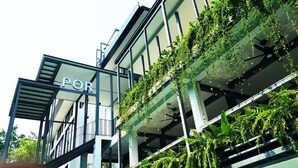 A modern building with a sign reading "POR" and balconies covered with greenery. - POR Santitham (Chiang Mai)