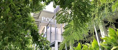 A building with a sign labeled "POR" amidst lush greenery.