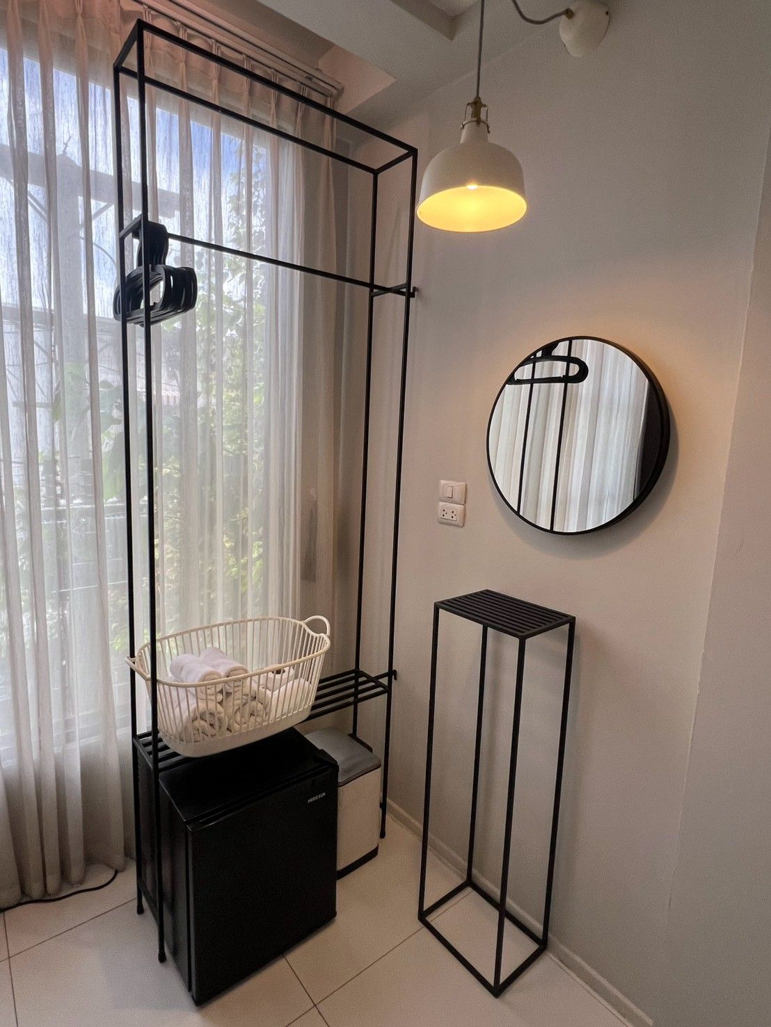 A modern room with a crib, a round mirror, and a pendant light.