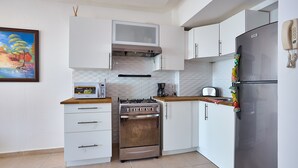 Una cocina moderna con armarios blancos, estufa de acero inoxidable y refrigerador.