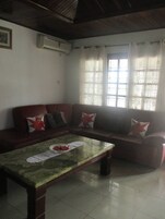 Una sala de estar con sofá, una mesa de centro y una ventana con cortinas.