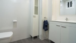Et badeværelse med toilet, håndvask og spejl.