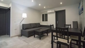 En moderne stue med en modulsofa, et spisebord med stole, en gulvlampe og en aircondition på væggen.