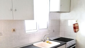 A kitchen with white cabinets, a black countertop, a sink, and an oven. - Hanioti Apartment (Kassandra)