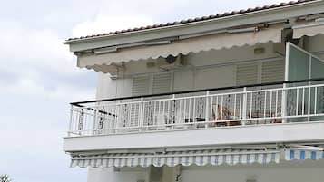 A two-story building with a balcony featuring white railings and a satellite dish.