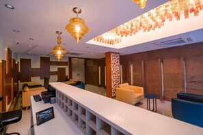 A modern hotel lobby with a long reception desk, comfortable seating, and stylish lighting fixtures. - JK Hotels (Coimbatore)