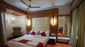 Una habitación de hotel con una cama grande, una silla, un escritorio y un espejo.