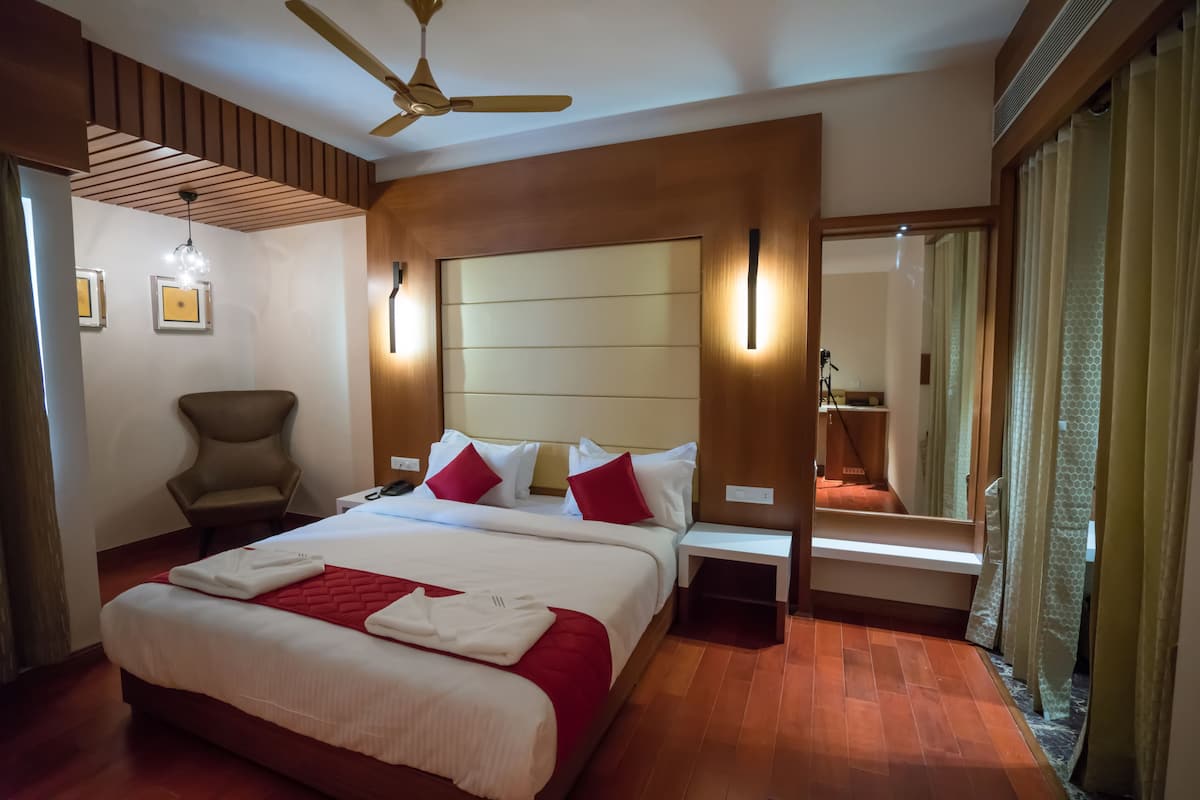 Ein Hotelzimmer mit einem großen Bett, einem Sessel, einem Schreibtisch und einem Spiegel.