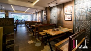 Un restaurante con mesas y bancos de madera, cuadros en las paredes y un suelo con diseño.