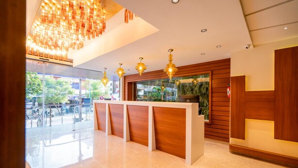 Una zona de recepción moderna con un mostrador de madera, lámparas colgantes y un amplio ventanal con vistas al exterior.