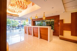 Una zona de recepción moderna con un mostrador de madera, lámparas colgantes y un amplio ventanal con vistas al exterior.