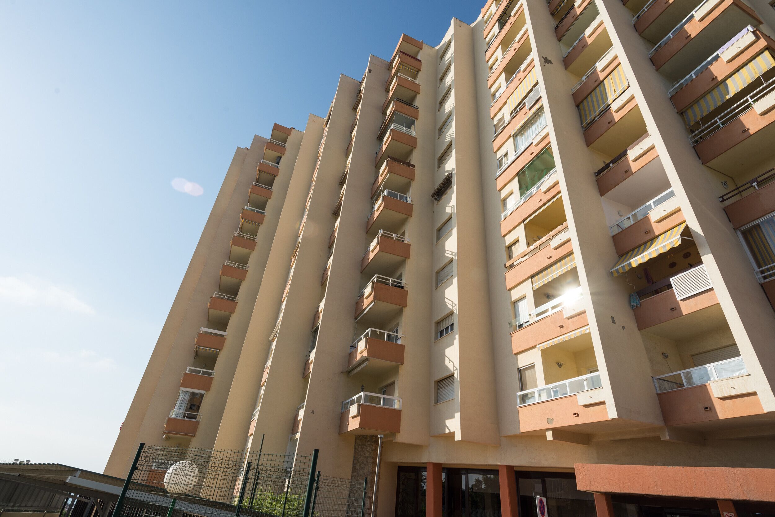 Un immeuble résidentiel de grande hauteur, doté de nombreux balcons, avec un ciel dégagé.