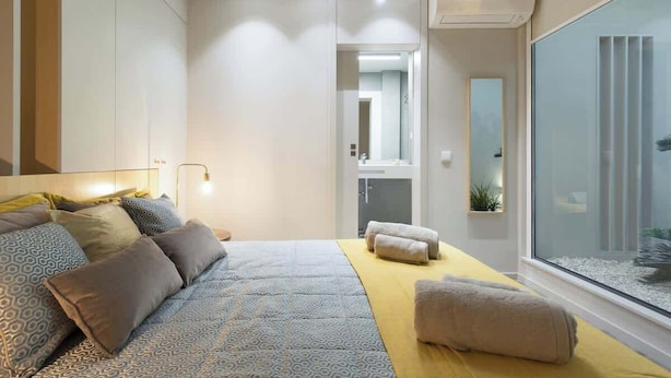A modern bedroom with a large bed, bedside tables, a mirror, and a view of a balcony.