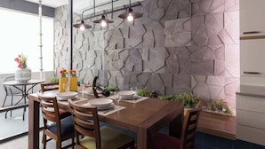 A dining area with a wooden table, chairs, and a modern wall with geometric patterns.