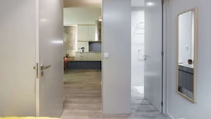 A modern kitchen with light wood flooring, a stone backsplash, and contemporary cabinetry.