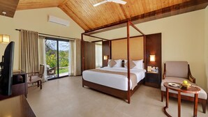 A spacious room with a four-poster bed, a television, a desk, and a chair.