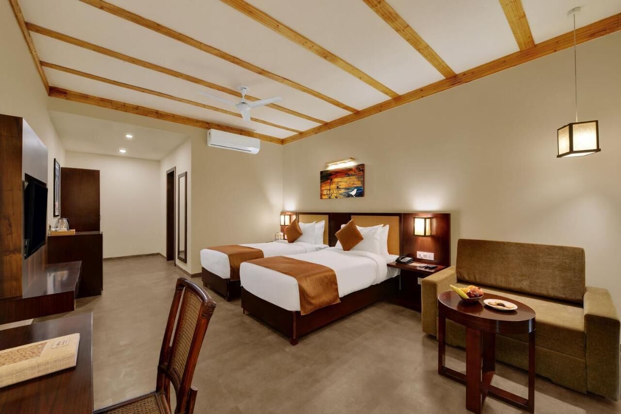 Una habitación de hotel con dos camas, un escritorio, un sofá y una mesita.