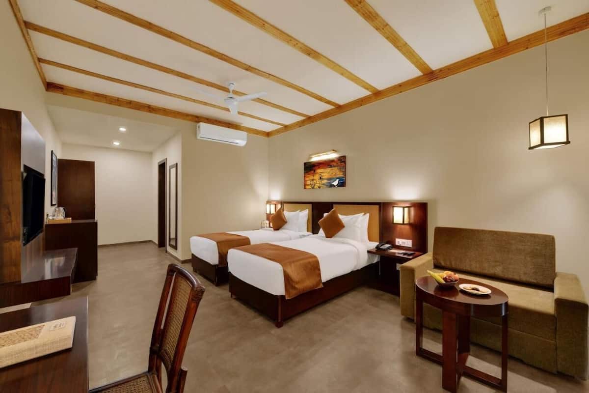 Una habitación de hotel con dos camas, un escritorio, un sofá y una mesita.
