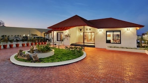 Ein modernes Haus mit rotem Dach, einer gepflasterten Auffahrt und einem angelegten Garten mit kreisförmigem Design.