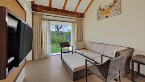 Ein modernes Wohnzimmer mit einem Flachbildfernseher, einer Couch, Korbsesseln und einem Deckenventilator.