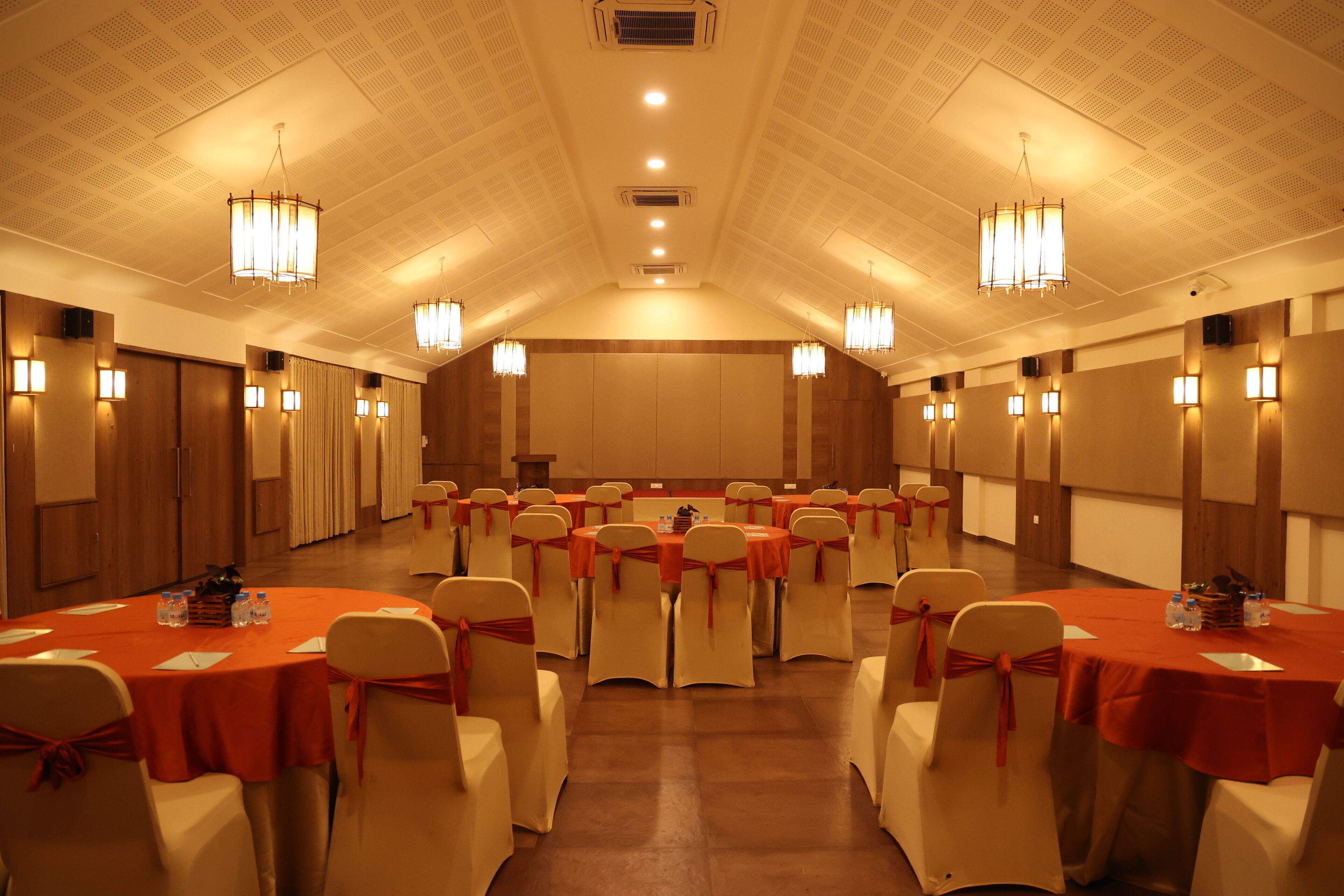 A conference room with round tables, white chairs, and red tablecloths.
