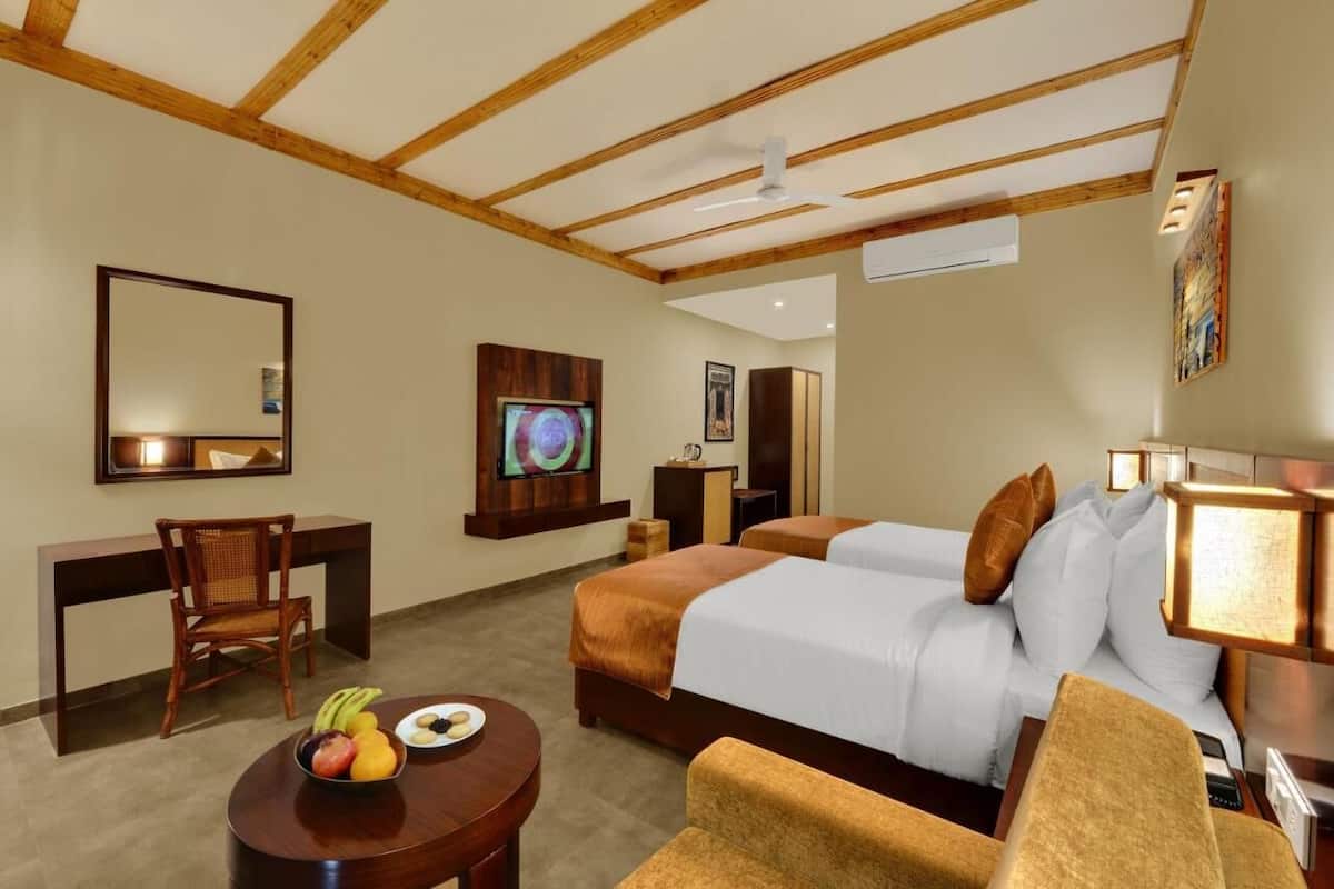 Habitación de hotel con dos camas, un escritorio, una silla, un televisor y un frutero.