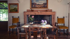 Ein Essbereich mit Holztisch, Stühlen, einem Kamin und zwei Bildern an der Wand.