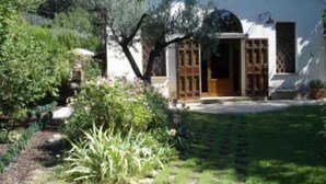 Ein rustikales Haus mit Garten, eine Holztür und ein Fenster mit Fensterläden.