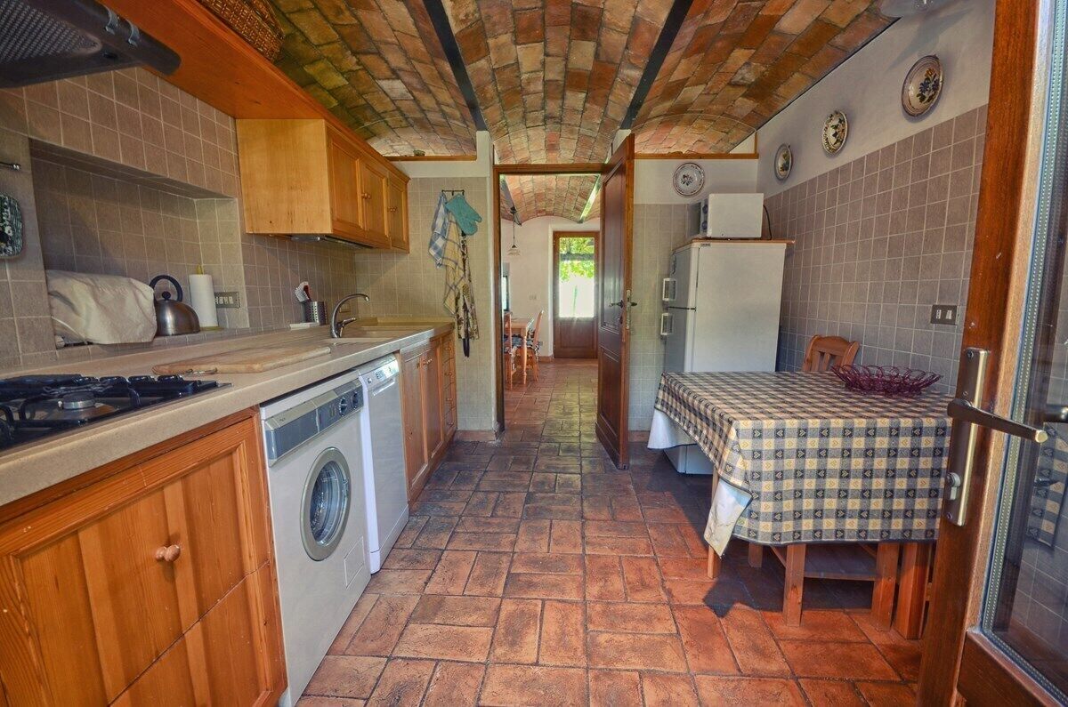 A compact kitchen with a washing machine, a stove, and a dining area with a checkered tablecloth.