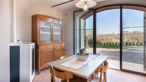 Een keuken met een eettafel, houten kastjes en uitzicht door grote glazen deuren.