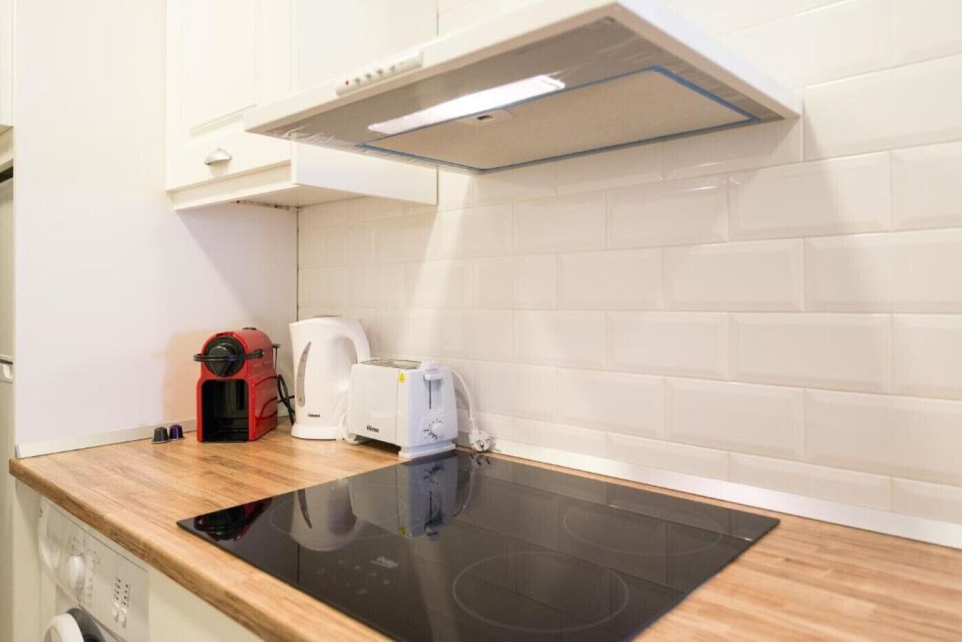 A kitchen with a black induction cooktop, a coffee maker, and a toaster.