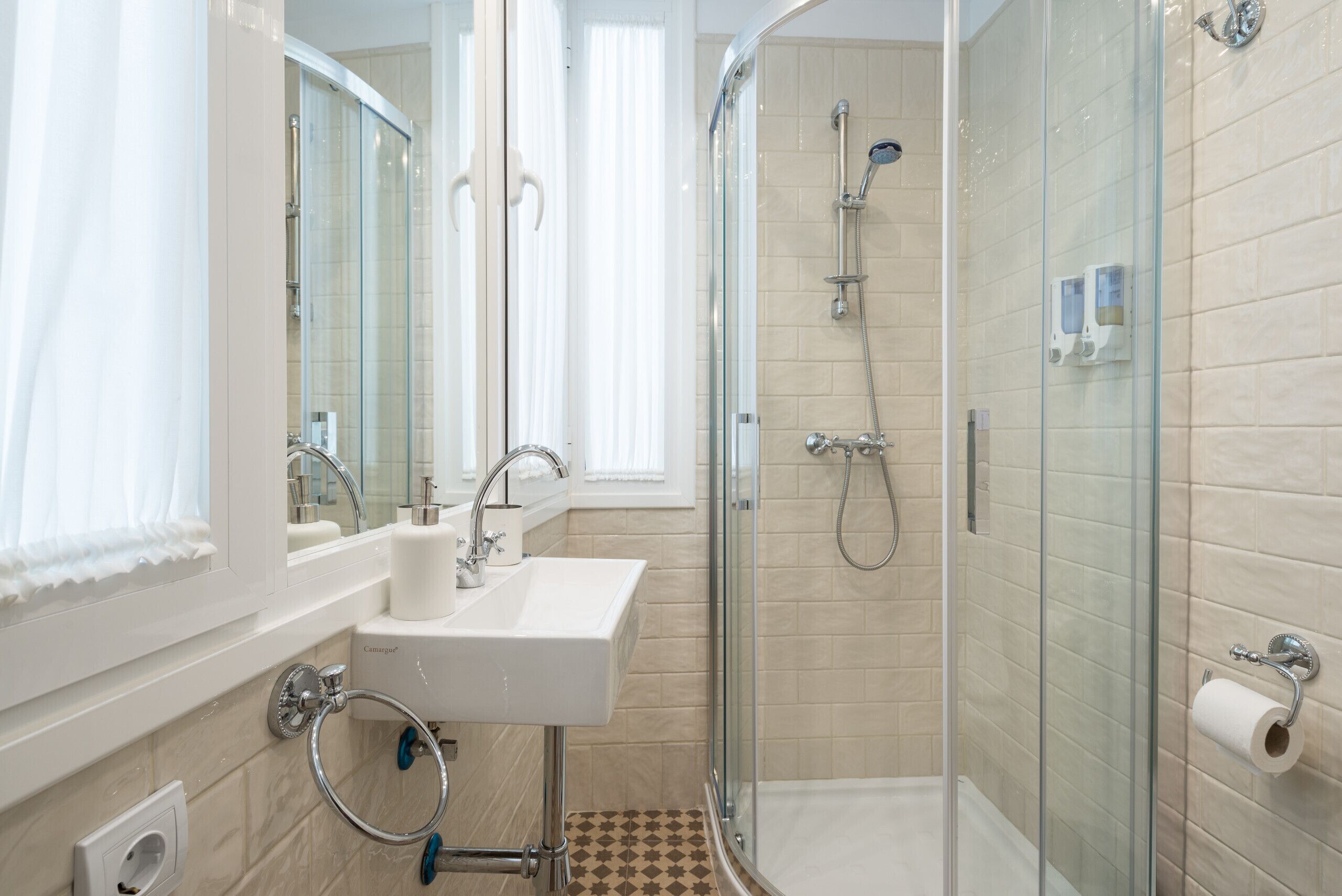 A modern bathroom with a glass-enclosed shower, a sink with a mirror, and a toilet paper holder.