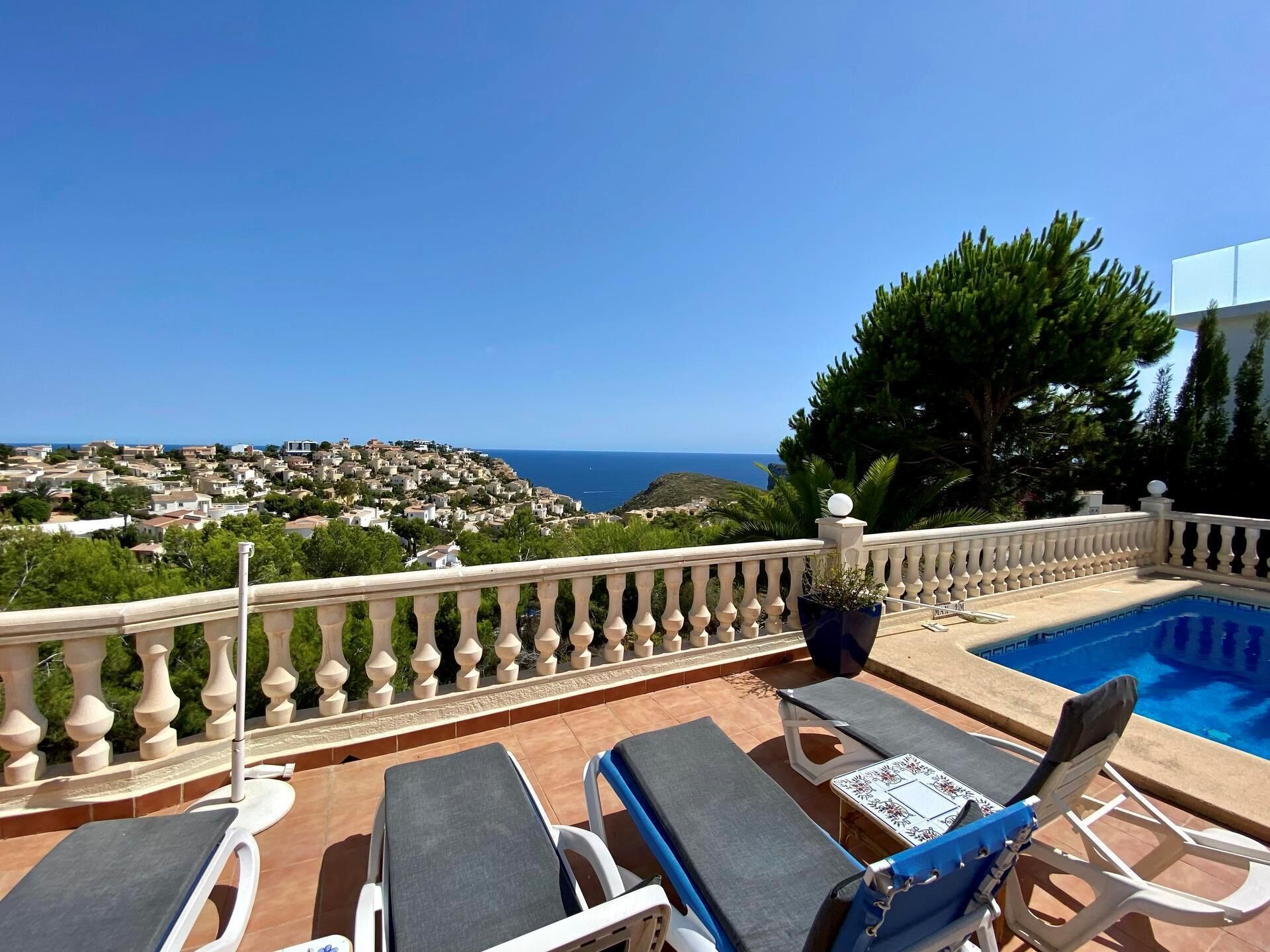 Eine Dachterrasse mit Pool, Liegestühlen und Blick auf die Küste.
